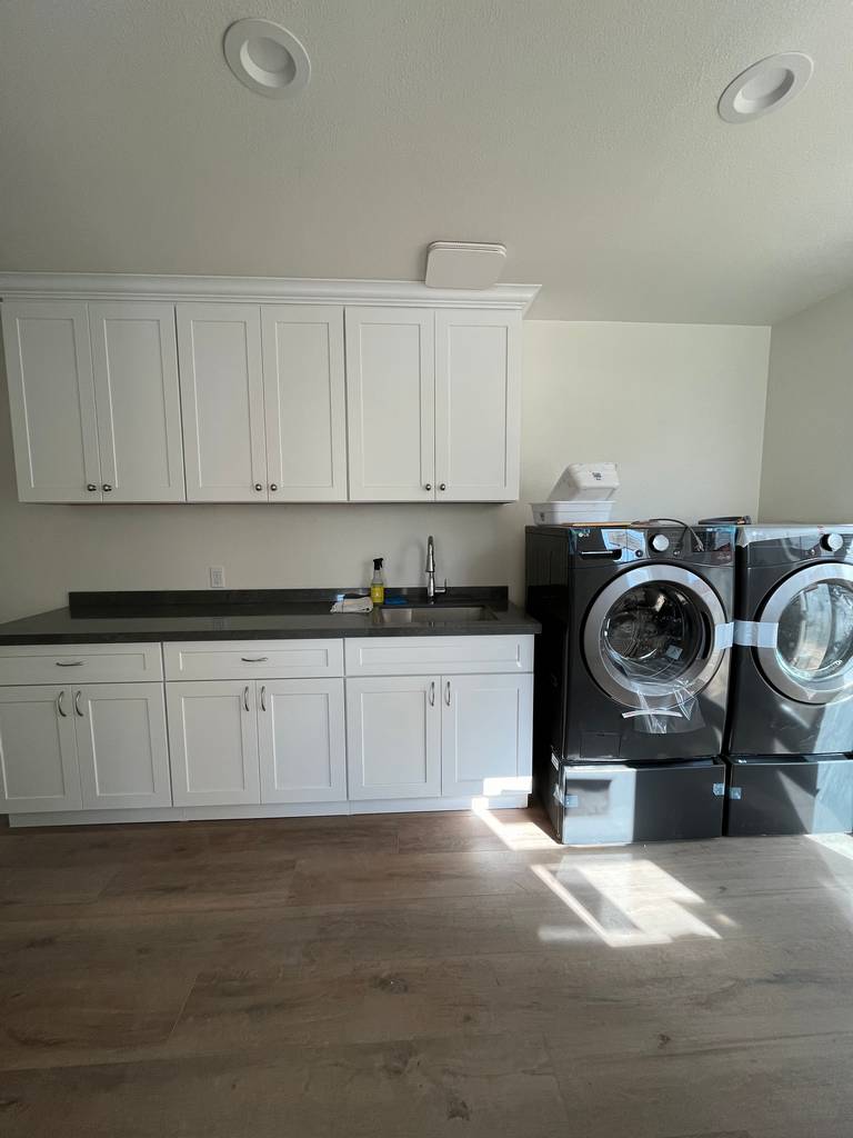 Custom cabinets floor-to-ceiling black marble countertops in completed laundry space.