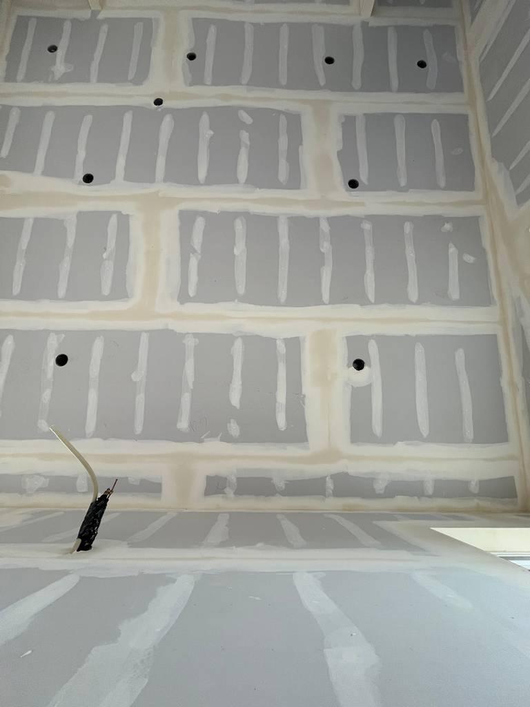 drywall installation with taped seams and electrical rough-in visible across the ceiling plane.