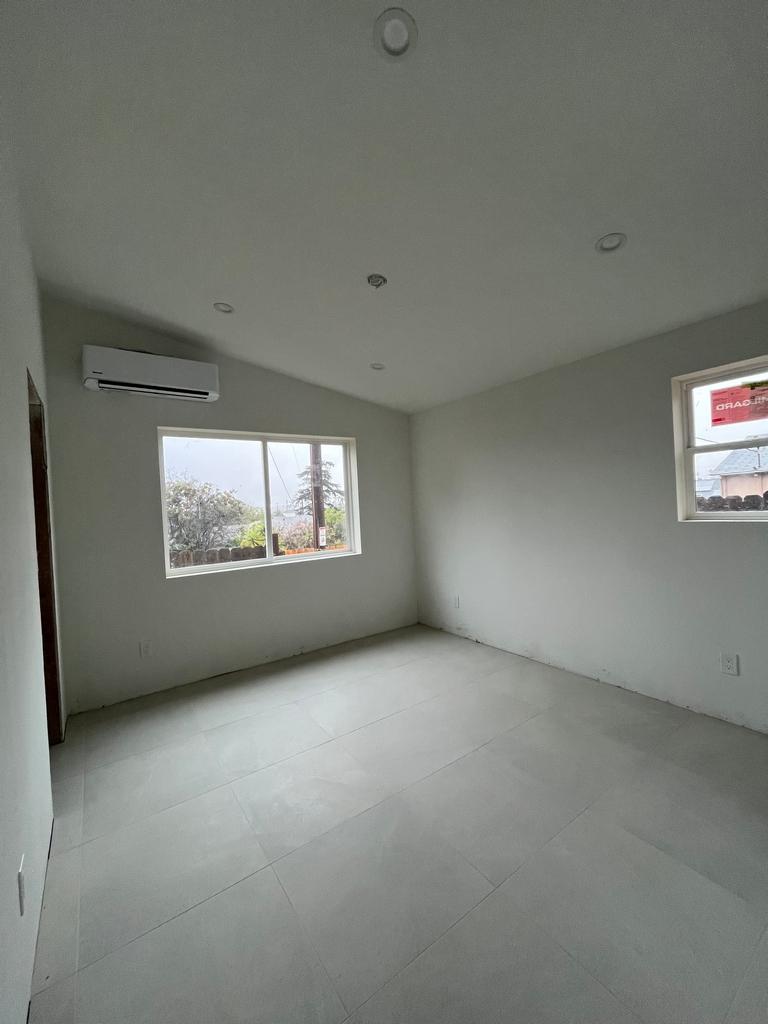 Bedroom with new tile floors, primed drywall, and mini-split.