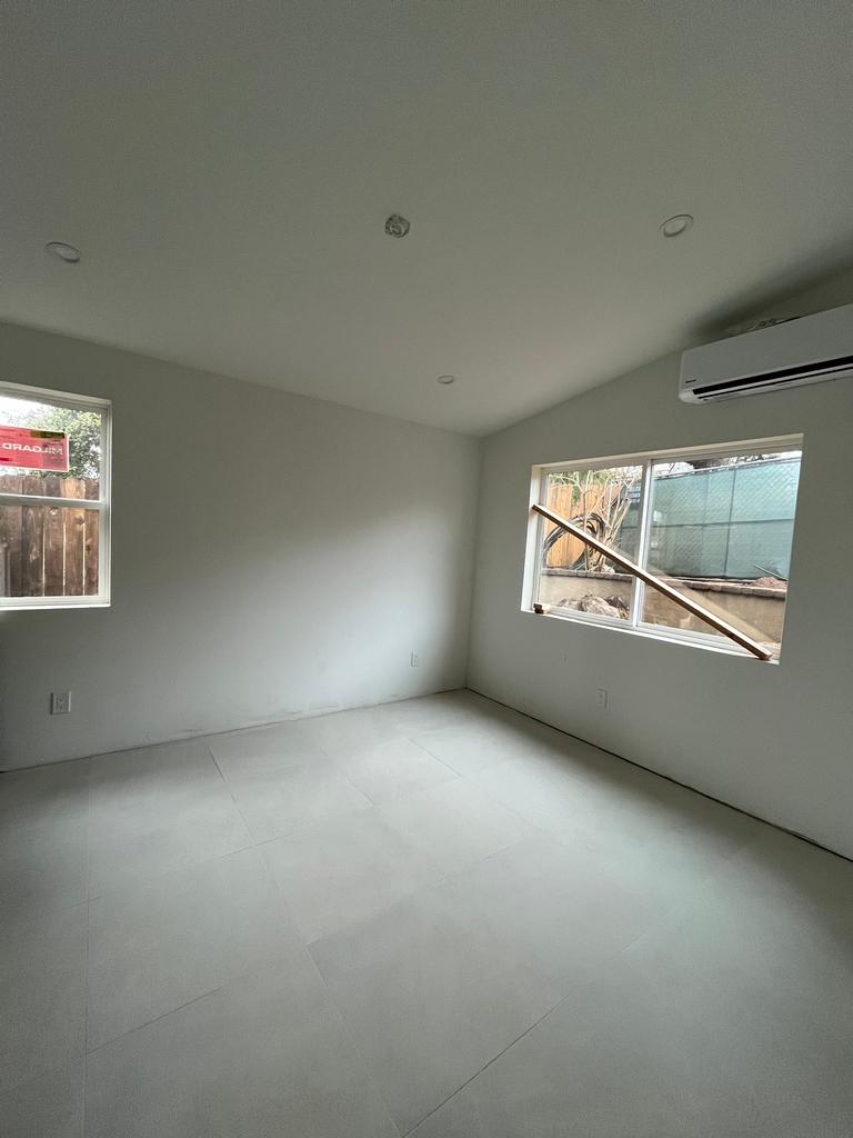 Finished bedroom with tile flooring, primed drywall, and recessed lighting.