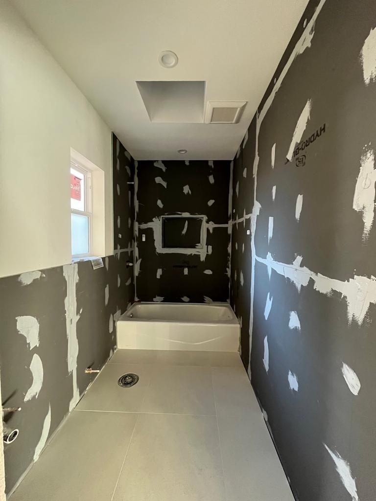 Bathroom with waterproof backer board, taped seams, tub, and tile floor.