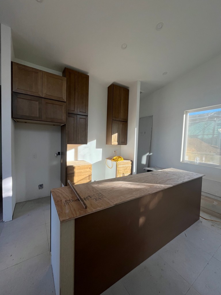 Kitchen base cabinets installed with island framing in progress.