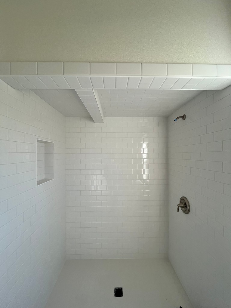 shower with white subway tile walls, tiled ceiling, recessed niche.
