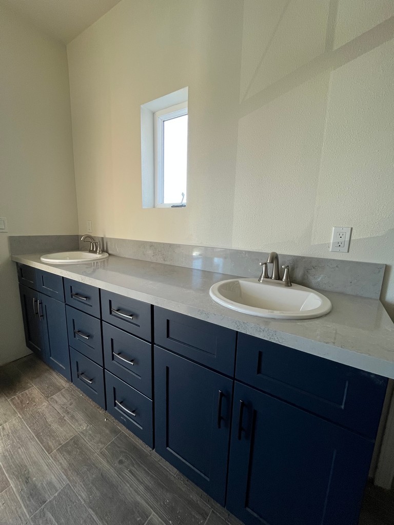 Double-sink bathroom vanity with blue cabinetry, stone countertop.