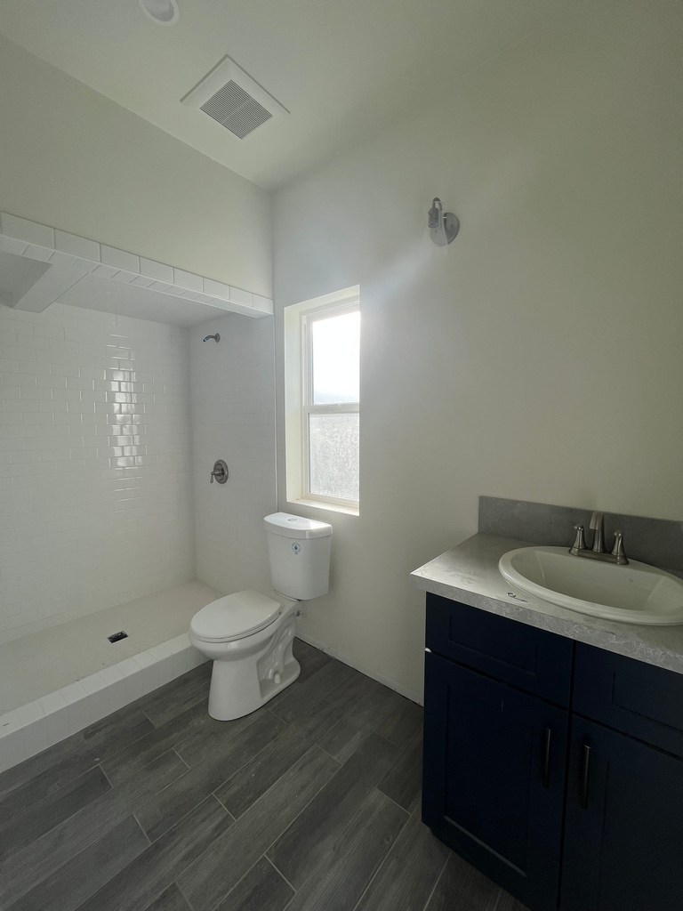 Finished bathroom with tiled shower, vanity, and toilet installed.