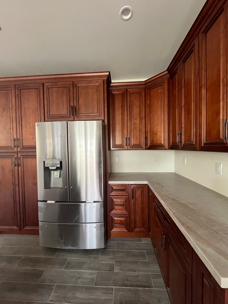 Finished kitchen with installed cabinets, countertops, and refrigerator