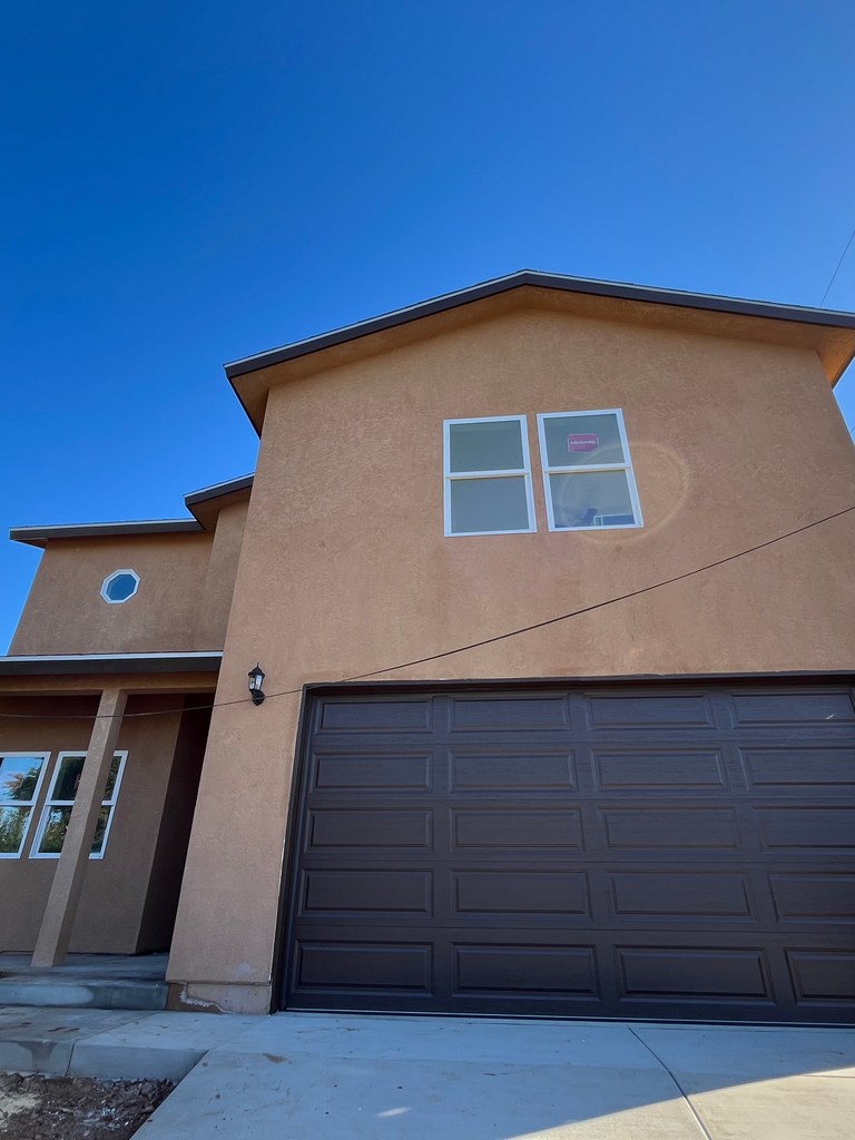 Finished residential stucco exterior with garage and windows.