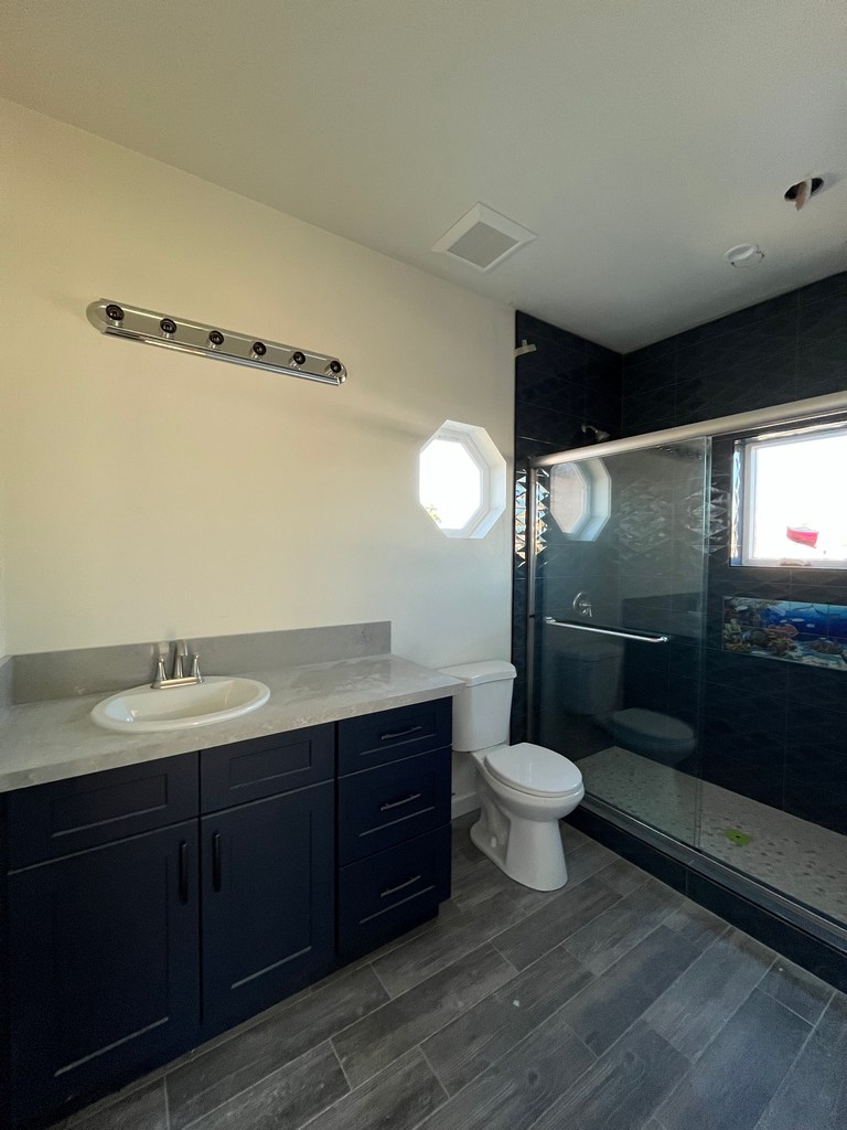 Finished bathroom with vanity, toilet, and tiled shower enclosure.