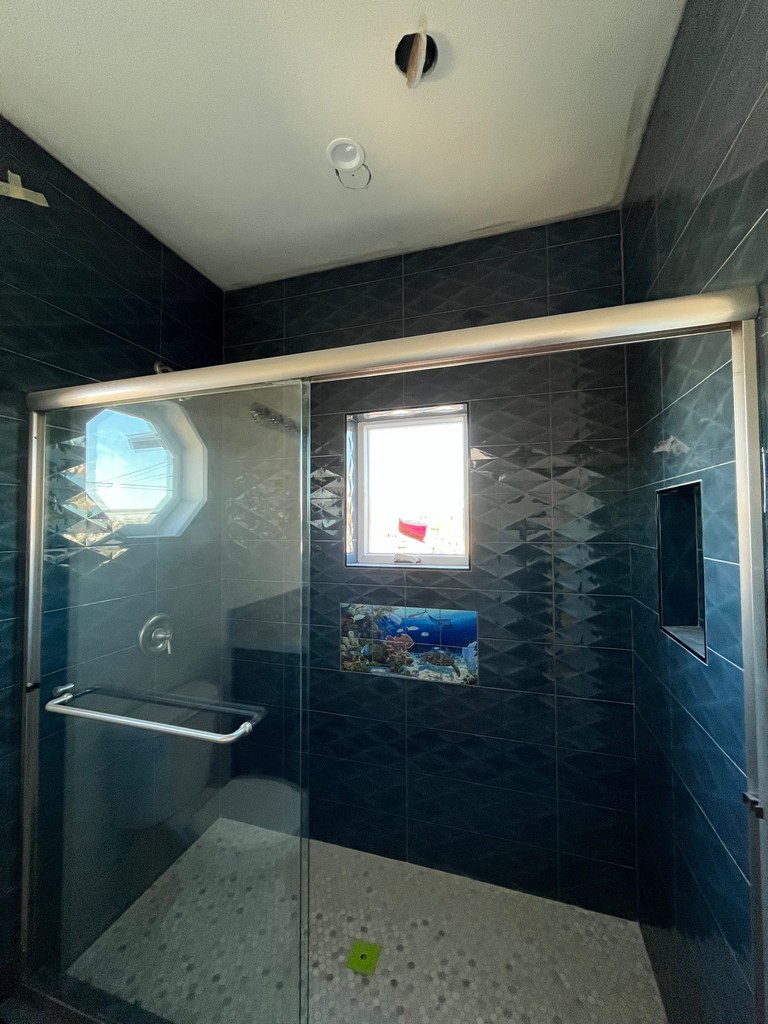 A finished tiled shower with glass enclosure and integrated shower niche.