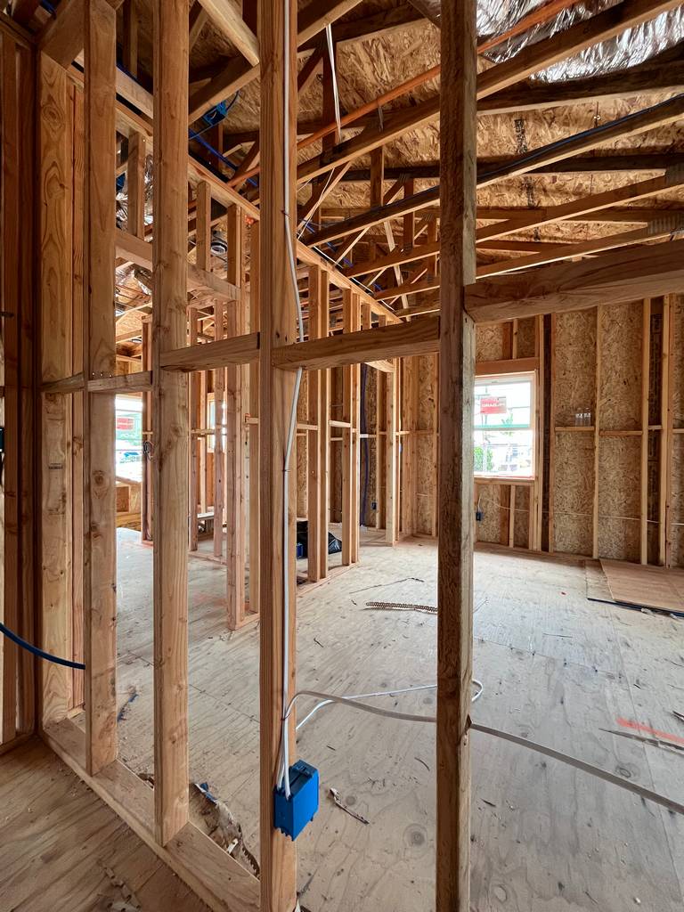 Hallway rough framing showing open studs, floor sheathing, and partial wall sections.
