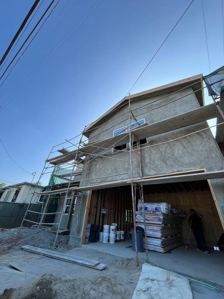 Garage area with exposed interior, stacked insulation, and scaffolding.