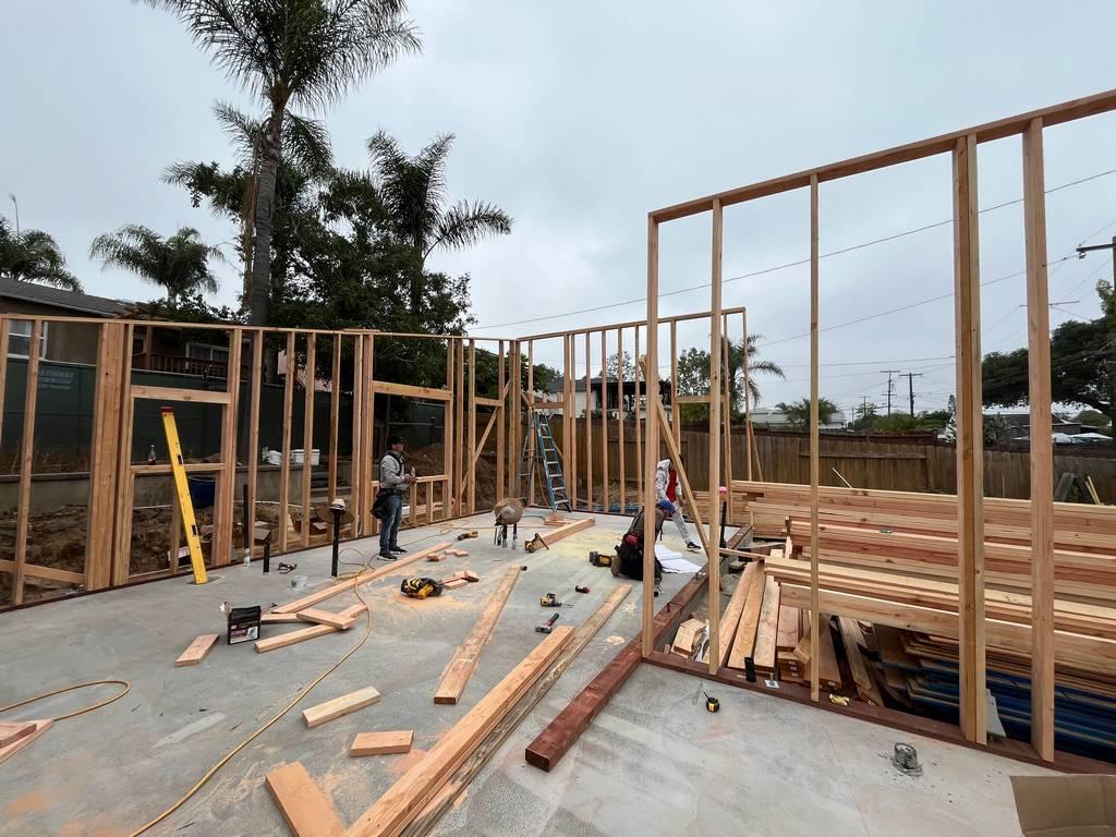 Interior view of active wall framing with tools and materials staged on slab floor.