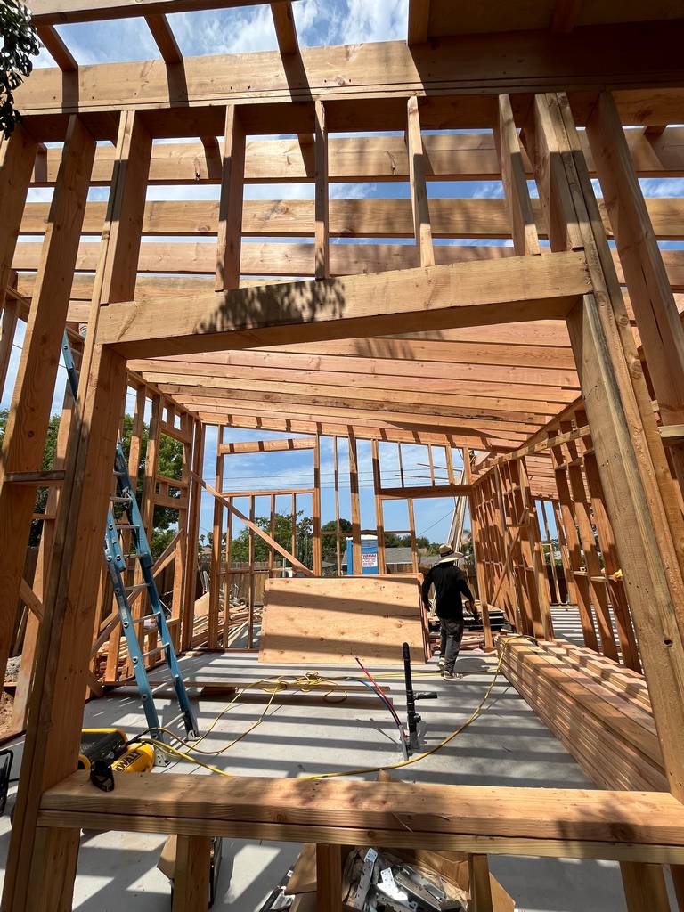 View through framed window cutouts shows partially completed walls and ceiling joists
