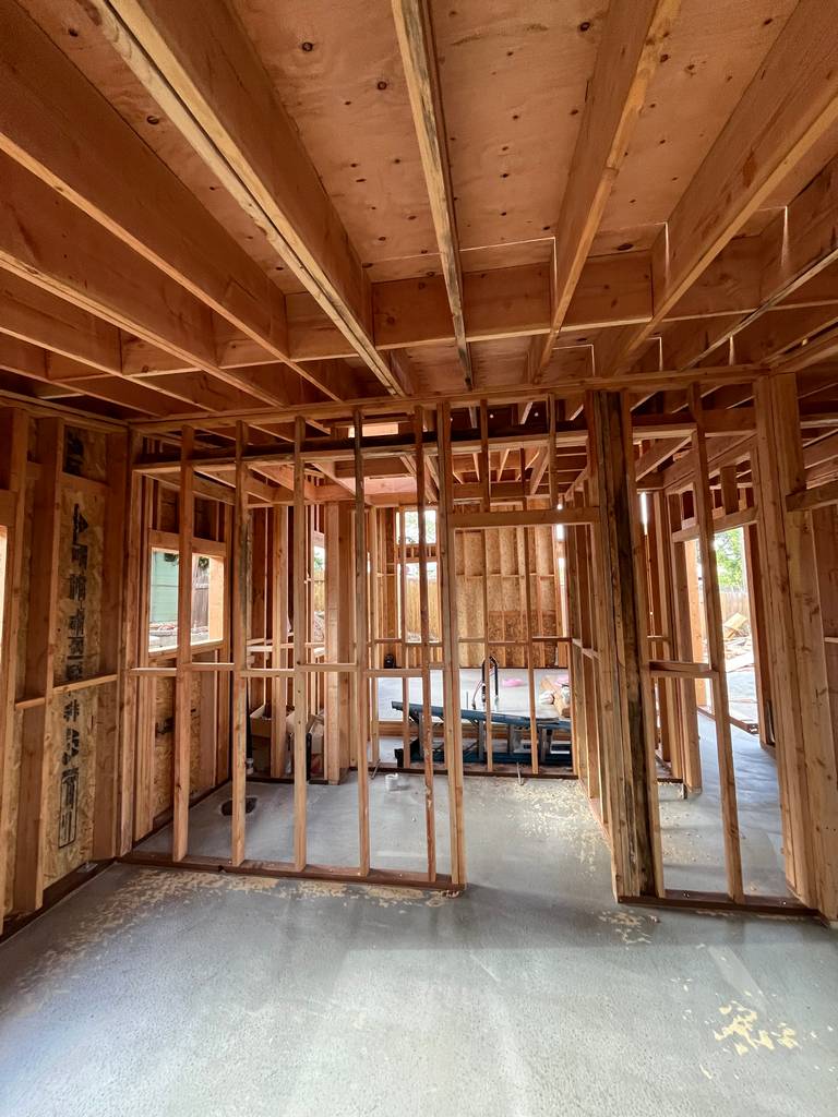 Open interior framed space showing multiple rooms and concrete flooring.