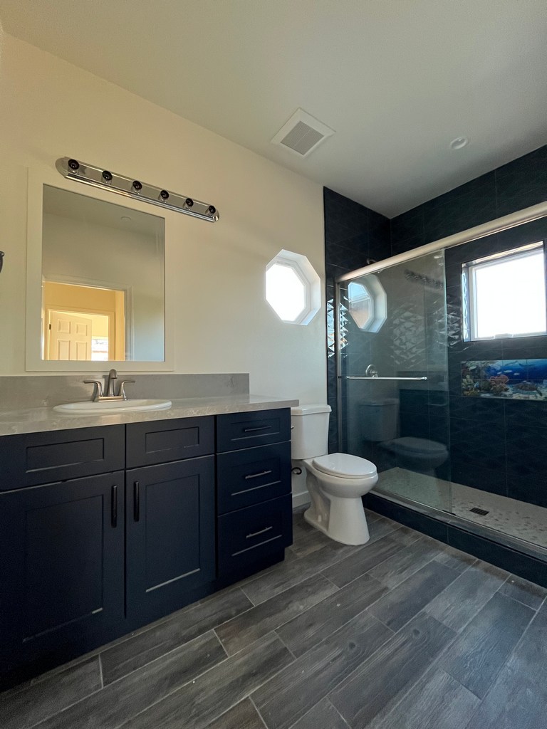 Finished bathroom with vanity, toilet, and glass shower enclosure