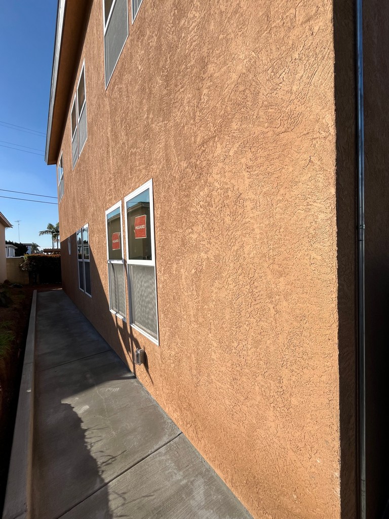Finished stucco exterior wall along side yard walkway on new residential construction