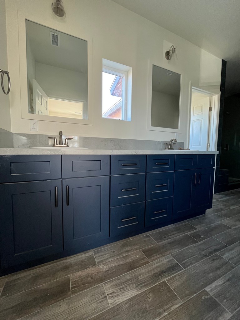 Finished primary bathroom with double vanity, mirrors, and tile flooring