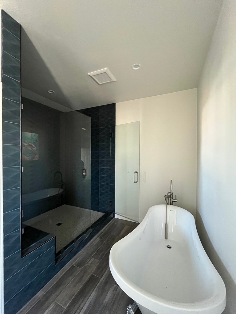 Finished primary bathroom with freestanding tub and tiled shower