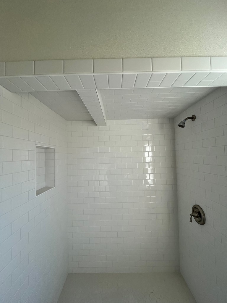 Finished shower with white subway tile walls and recessed niche.