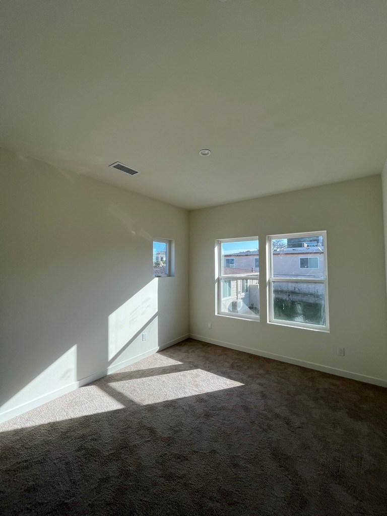 Completed bedroom interior with windows and carpet flooring.