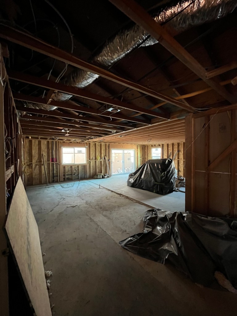 Open-plan remodel area with exposed ceiling framing and protected floor slab.