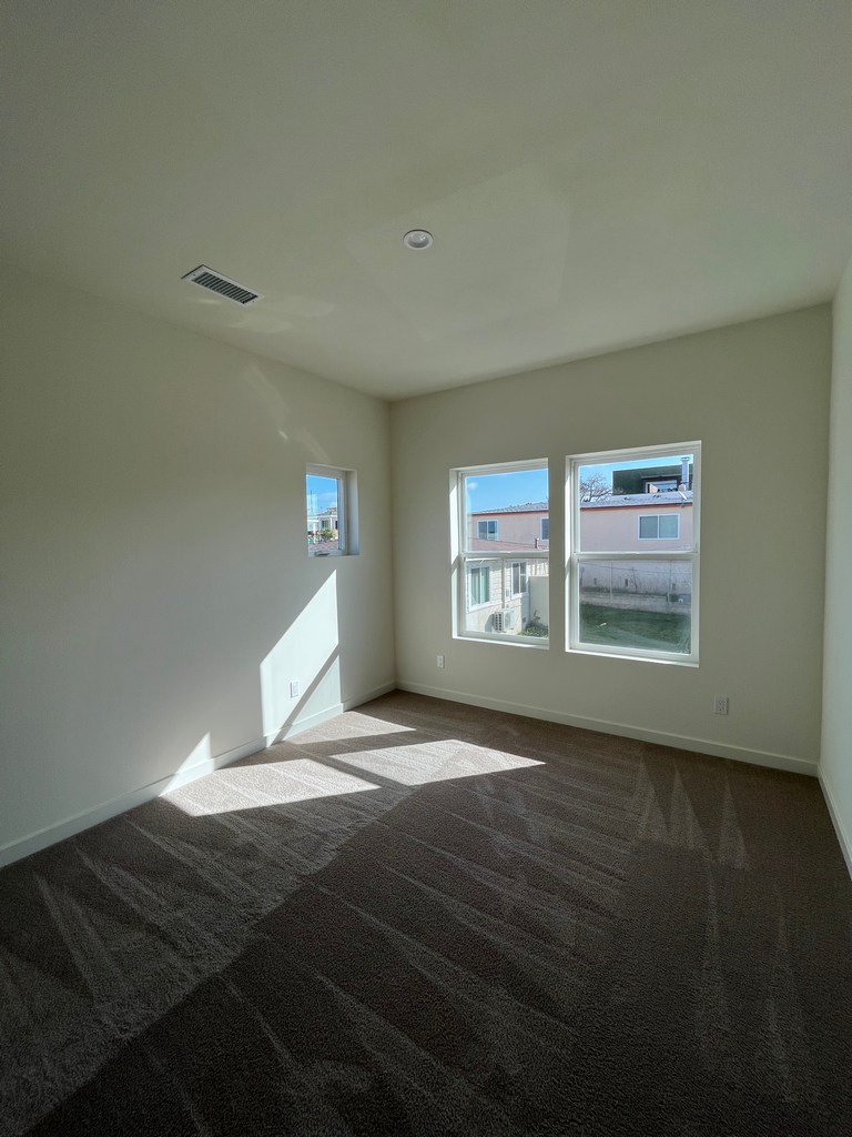 Finished bedroom space showing carpet installation, painted drywall, base trim, and window openings.
