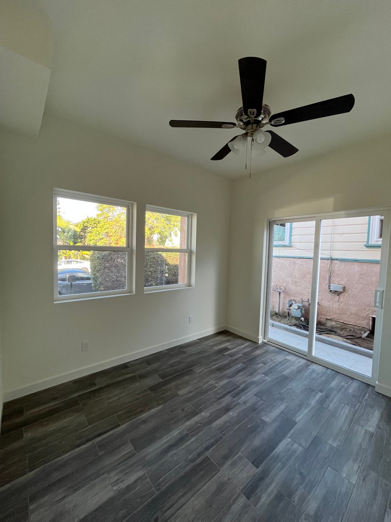 Interior room showing sliding glass door, plank flooring, ceiling fan fixture.