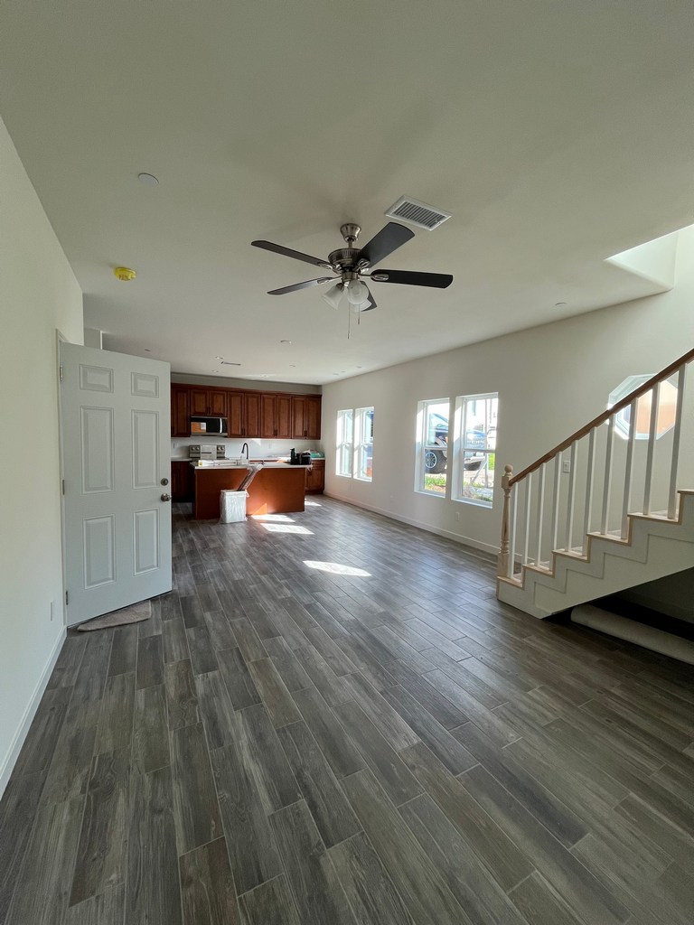 Open floor plan interior connecting living area and kitchen with plank flooring.