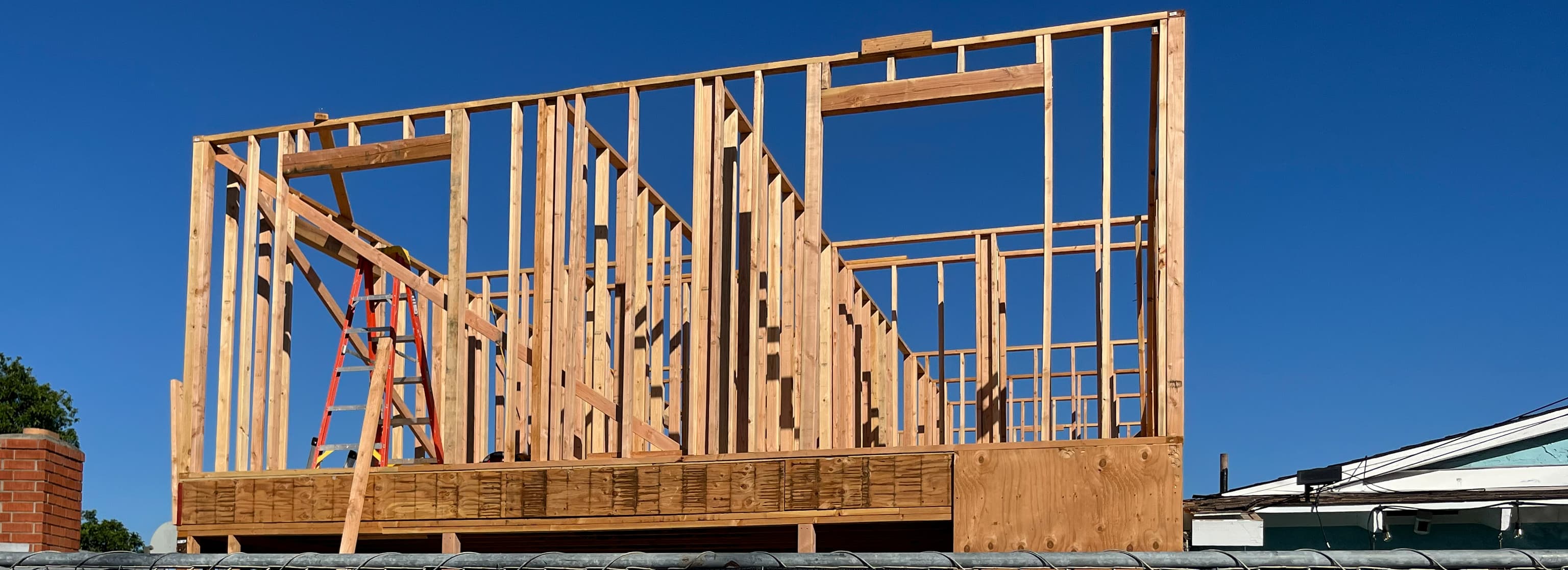 ADU wall framing above the existing garage shows window openings and structural lumber.