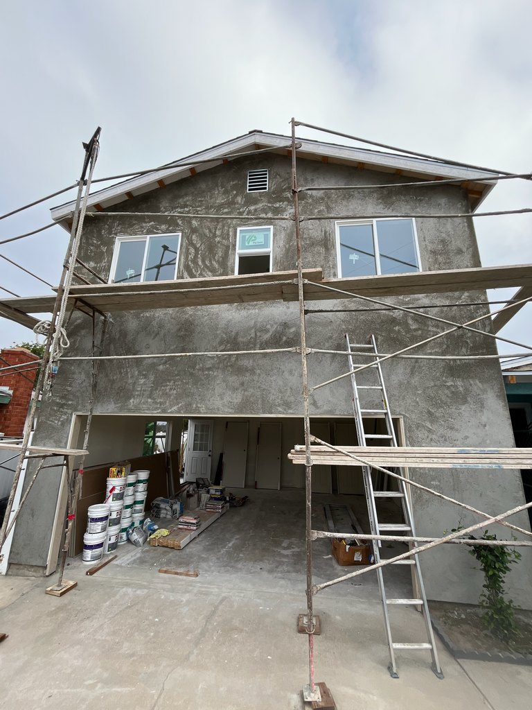 tucco base coat, upper-level windows, roof vent, scaffold platforms