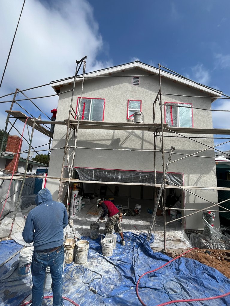 Construction workers apply the exterior stucco finish while windows