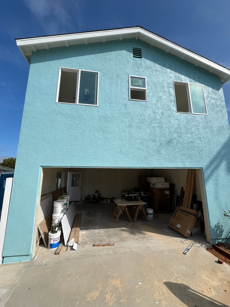 stucco finish, white roof trim, upper-level windows, wall vent