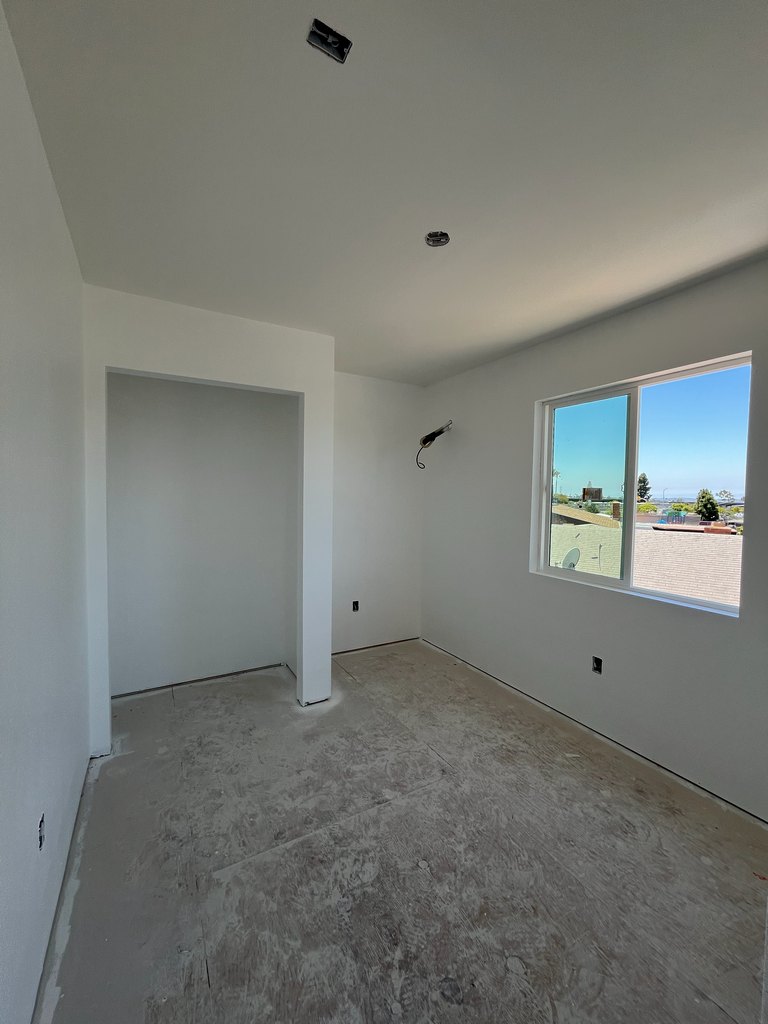 Upper-level room with completed white drywall and paint, a framed closet opening