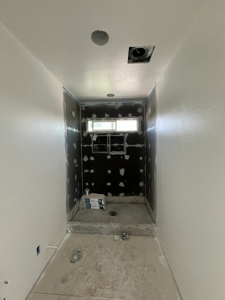 Bathroom construction view showing the raised shower base, prepared wall panels