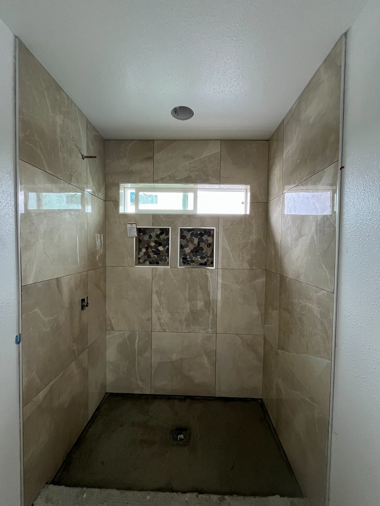 Large-format shower tile with pebble niches