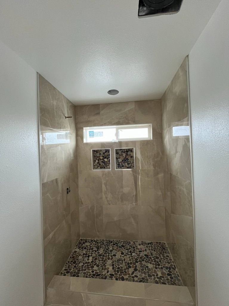 Tiled bathroom leading to pebble shower