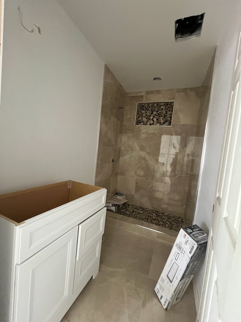 Vanity cabinet beside pebble-tile shower