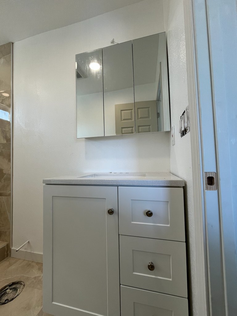 Installed vanity cabinet and three-panel mirror