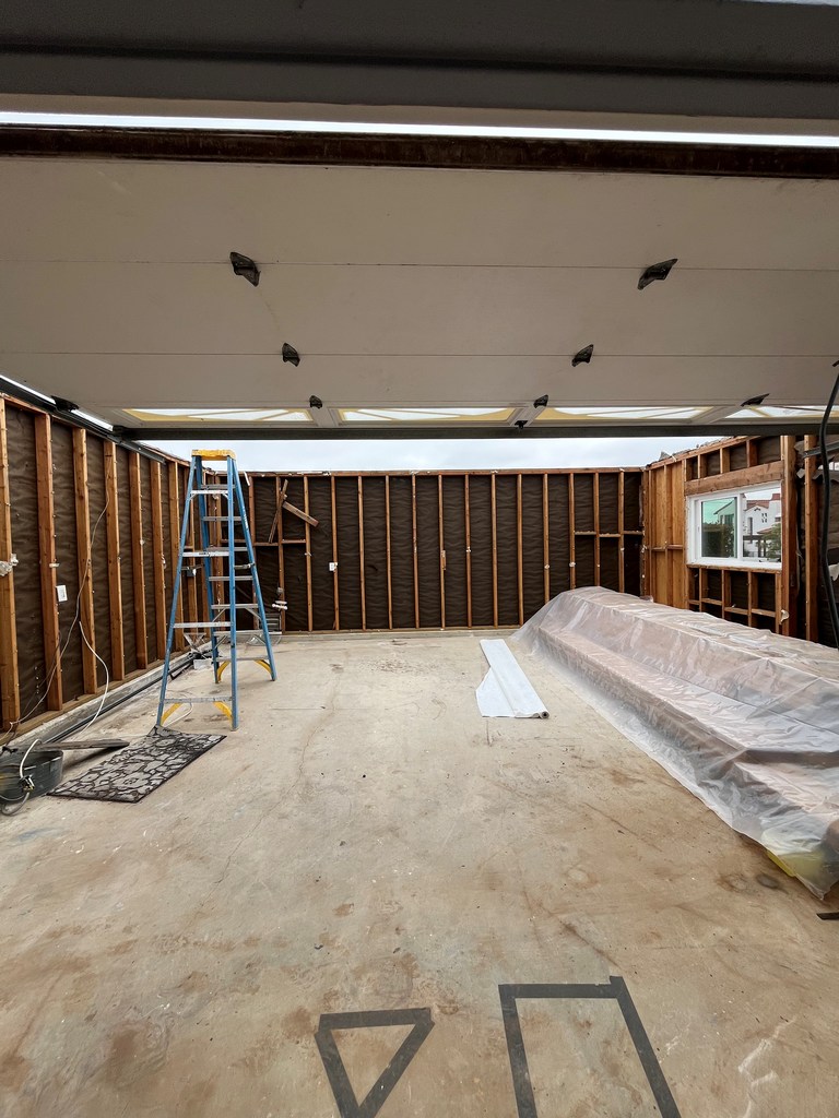 Open-roof garage interior with exposed framing during recreation room conversion
