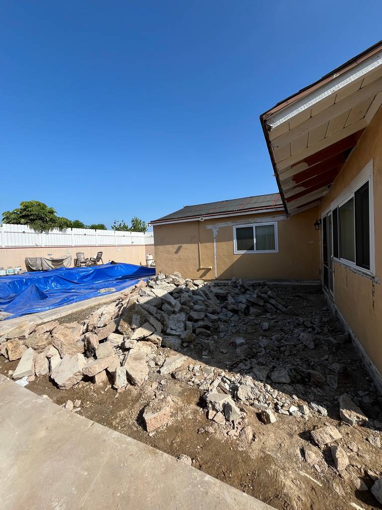 View of backyard construction area with large debris pile from slab removal.