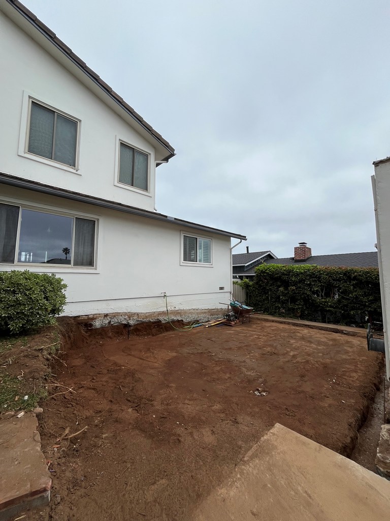Wide excavated addition footprint beside existing two-story house