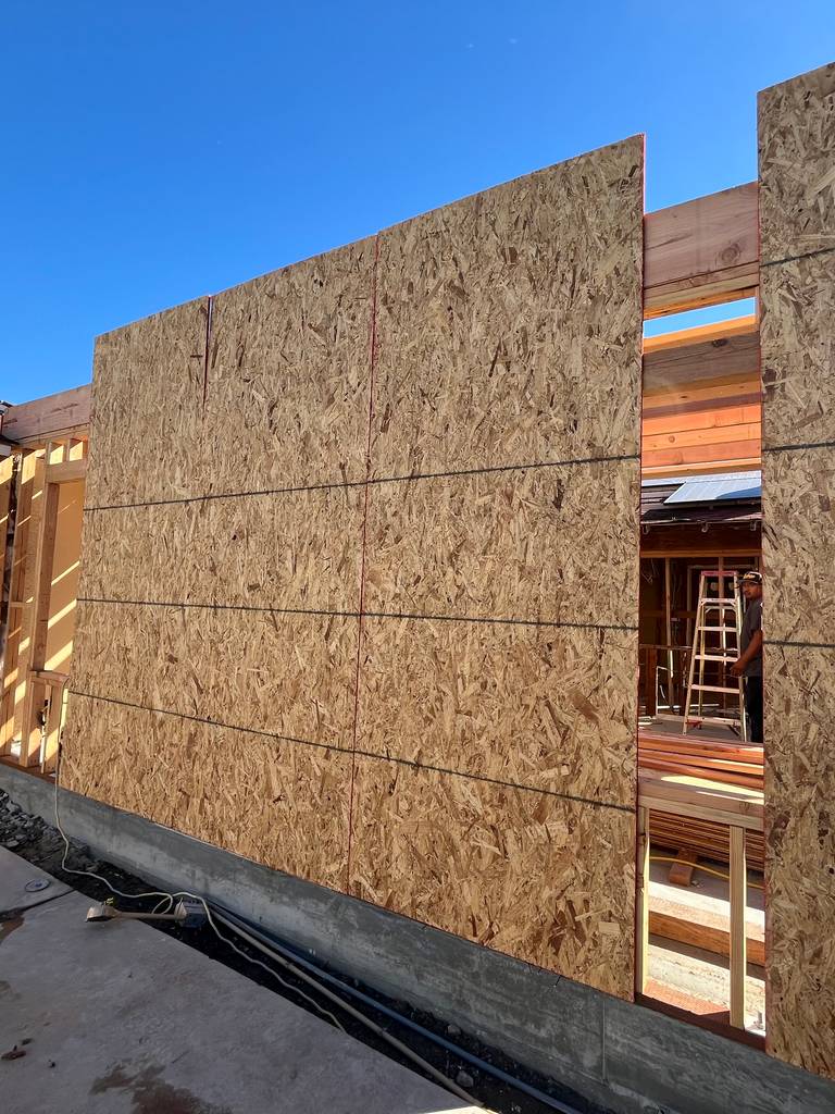 OSB wall sheathing installed on new framing structure with visible rough opening.