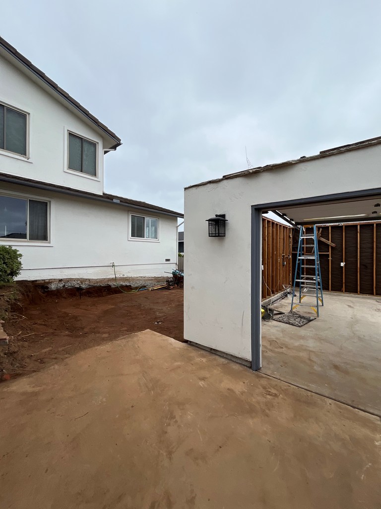 Open detached garage beside excavation for new house connection