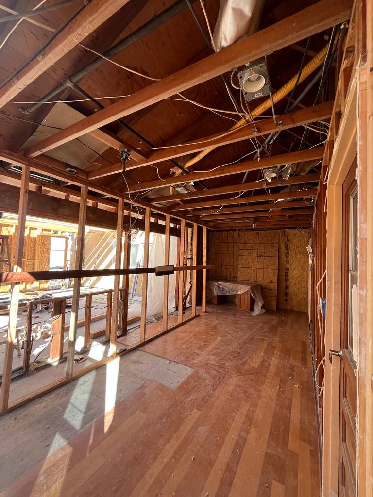 Interior framing with open ceiling joists and exposed electrical rough-in during remodel.
