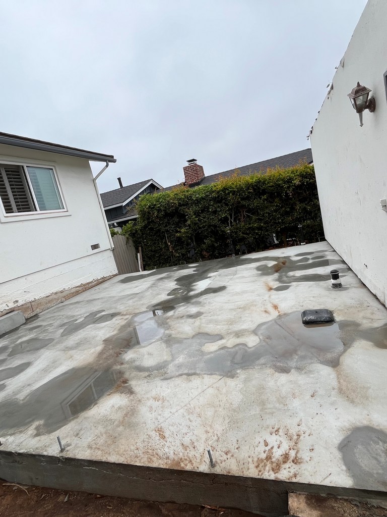New concrete connector slab with utility penetrations between house and garage