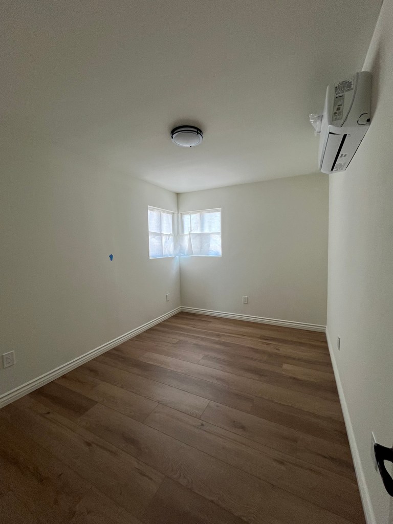 Finished bedroom renovation featuring new wood-look flooring.
