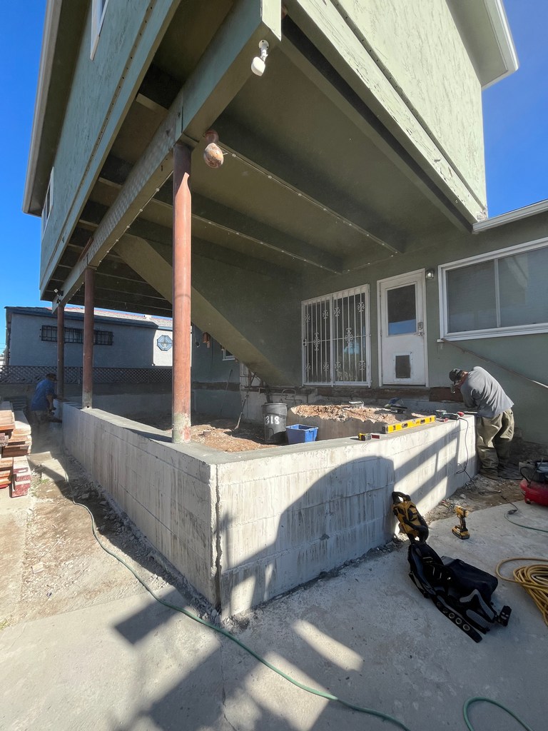 Newly poured concrete foundation walls forming the perimeter of the addition after formwork removal.