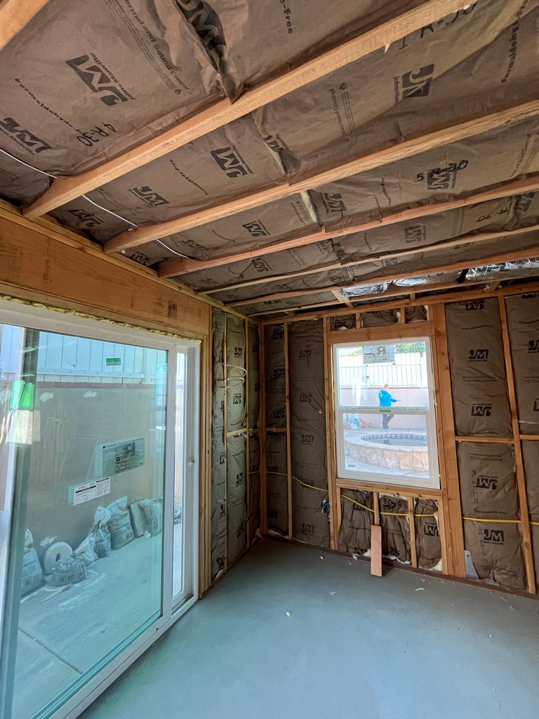 Fiberglass battsFiberglass batts installed in walls and ceiling of framed room with window and slider.