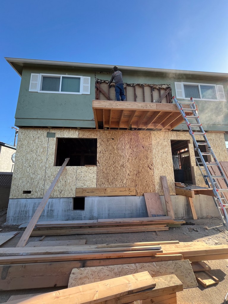 Upper-level exterior wall opened for structural modification and integration with new addition.