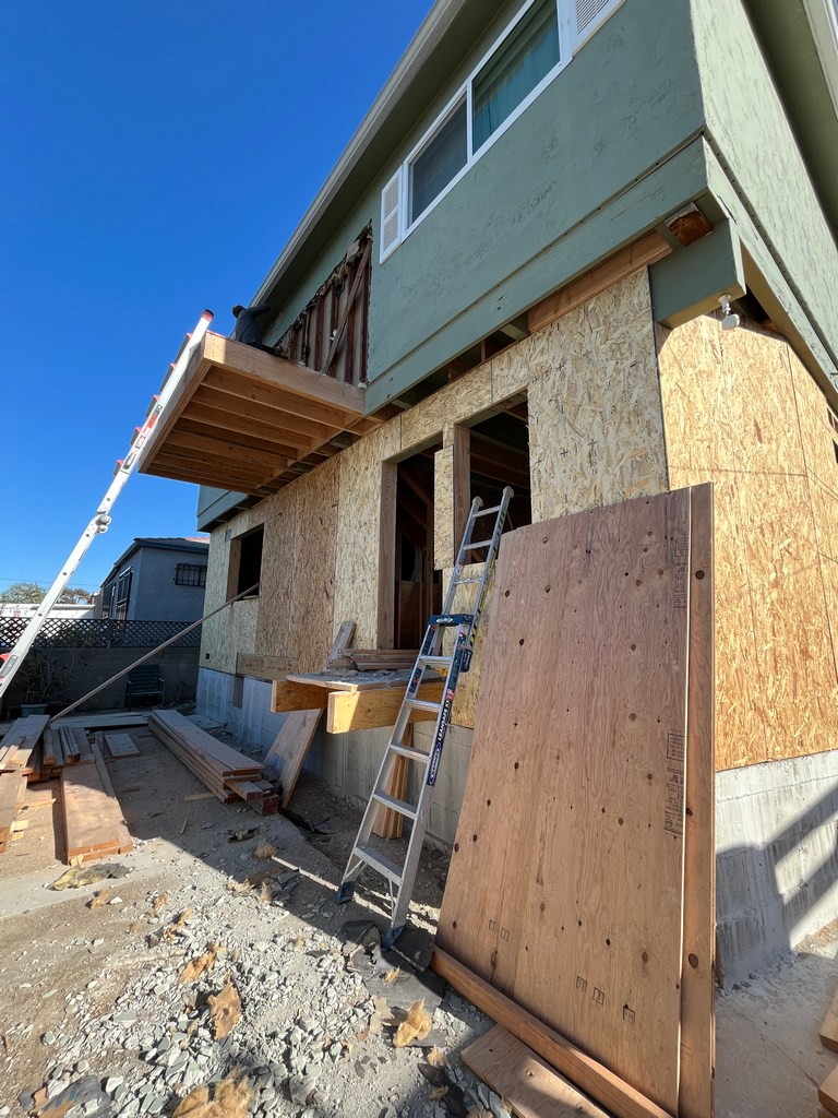 Wall sheathing installed with rough openings for windows and doors in the addition.